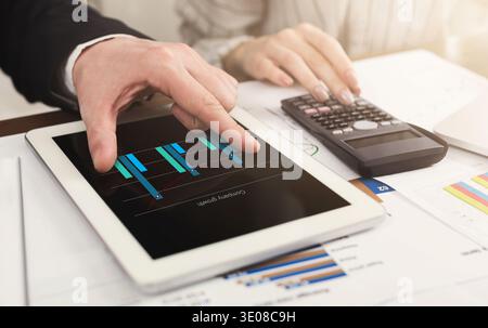 Colleagues counting finances on tablet and calculator Stock Photo