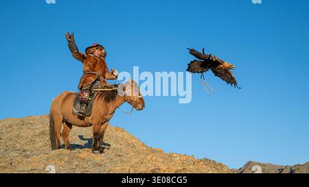 Golden Eagle taking off from a Mongolian eagle hunter (berkutchi) on a horse, Altai Mountains, Western Mongolia, Mongolia Stock Photo