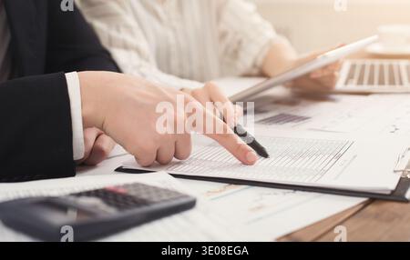 Business colleagues checking documents and using calculator Stock Photo