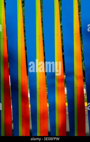 Brightly colored vertical fence panels featuring an abstract design with blue, orange, green, and red stripes, adding vibrant visual interest. Stock Photo