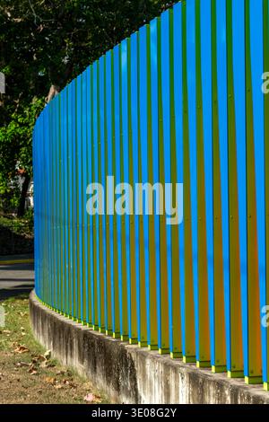 Blue and green vertical panels forming a contemporary art fence with geometric design creating a bright, abstract background in an outdoor urban park. Stock Photo