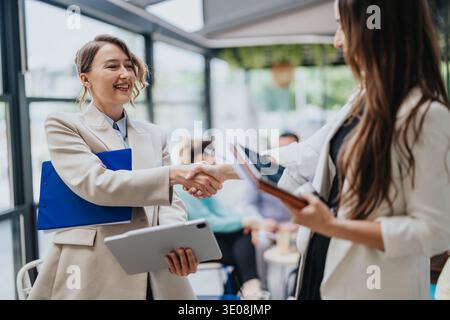 Business collaboration handshake between two female professionals during a meeting in a modern office Stock Photo