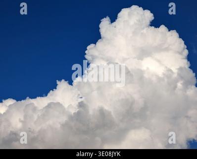White and fluffy cumulus clouds towering against a clear blue sky Stock Photo