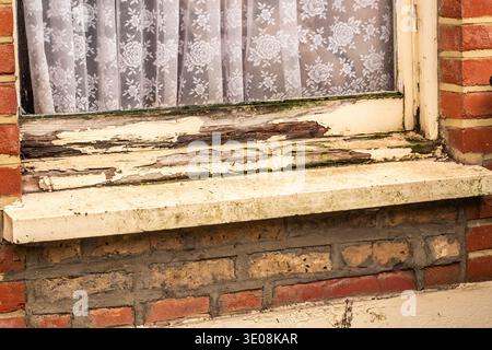 LONDON - Rotten peeling wooden window frame on red brick house exterior Stock Photo