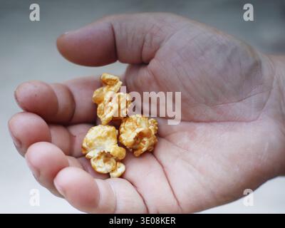 Caramel-coated popcorn placed on a person's palm. Stock Photo