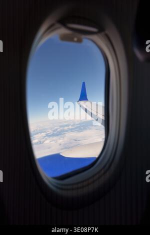 View from airplane wing and clouds from window seat during flight Stock Photo