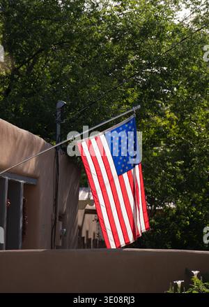 flag of united states of america usa flag stars and stripes flag of U.S.A. hanging in front of adobe style home in santa fe new mexico patriotism Stock Photo