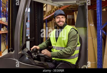 Forklift operator driving in warehouse, logistics worker in high visibility vest Stock Photo