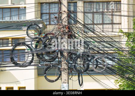 Power wire and communication, telephone, internet cable tangled up on the electric utility pole in suburban Stock Photo