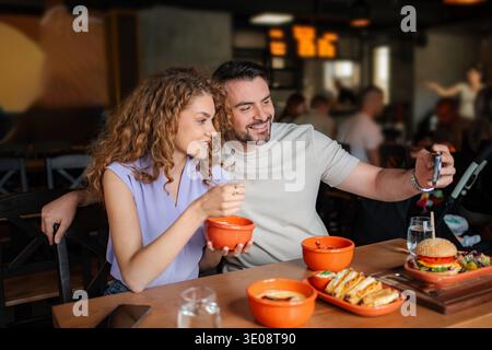 Young couple taking selfie while having lunch at restaurant Stock Photo