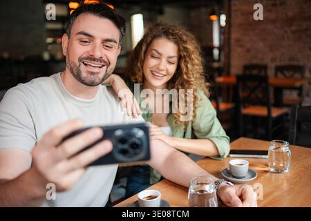 Happy couple taking a selfie while having coffee at a cafe Stock Photo
