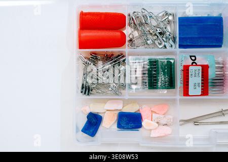 Organized sewing notions box with pins needles chalk and thimbles on white surface Stock Photo