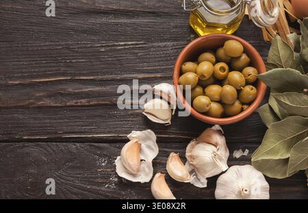 Collection of Olives, Garlic, and Herbs Arranged on a Wooden Table for Preparation of a Dish Stock Photo