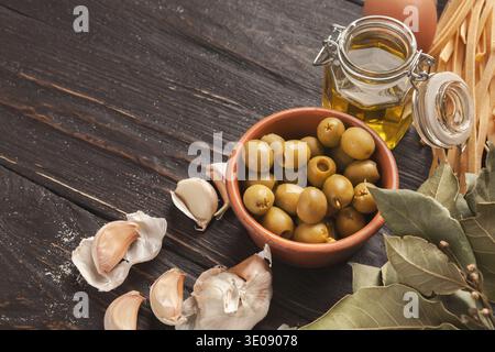 Collection of Olives, Garlic, and Oil Displayed on a Wooden Surface in a Kitchen Setting Stock Photo