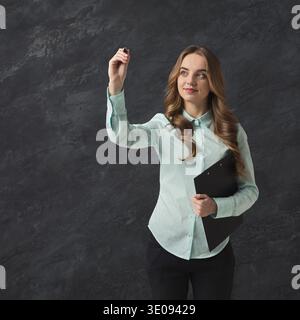 Smiling woman writing something in air with marker Stock Photo