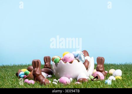 Easter egg hunting background with chocolate eggs. Various candy and chocolate Easter eggs, bunny and rabbits with basket for eggs on green grass park Stock Photo