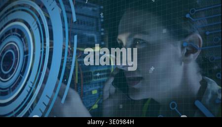 Reaching female technician adjusting patch cables in rack in lab, HUD overlay, wearing hivis strap Stock Photo