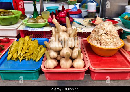 Kuznechnyy Rynok Market in Saint Petersburg shows various vegetables and ingredients. Fresh garlic and peppers are displayed on colorful trays. Stock Photo