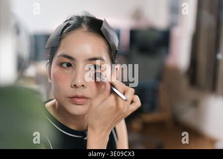 Closeup portrait of attractive asian female getting ready applying cosmetics, brush for facial makeup, dialy grooming, cosmetic application and self c Stock Photo