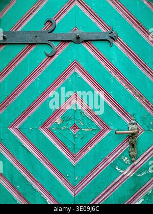 Old wooden church door with colourful paint in turquoise and magenta Stock Photo