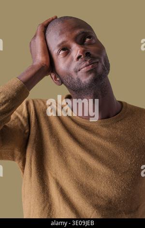 Portrait of thoughtful African man looking upward with hand on head against neutral background, concept of thinking, problem solving, idea and decisio Stock Photo