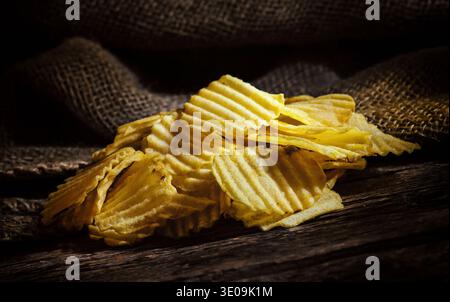 Crispy Potato chips on rustic wooden table. Stock Photo