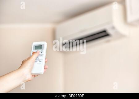 Closeup of a hand using a remote to activating air conditioning machine. Stock Photo