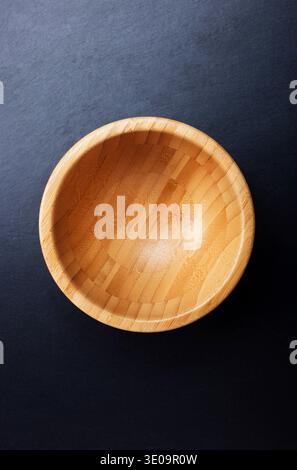 Top view of an empty wooden bowl on black table. Stock Photo