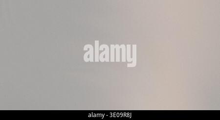 A close-up view of a light gray, subtly textured surface. The lighting creates a slight gradient from left to right, adding depth to the fine grain pa Stock Photo