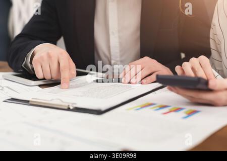 Business colleagues checking documents and using calculator Stock Photo