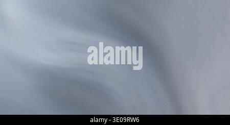 A close-up of a wavy grey fabric texture featuring smooth folds and creases, creating a soft and natural visual effect with gentle curves and subtle s Stock Photo