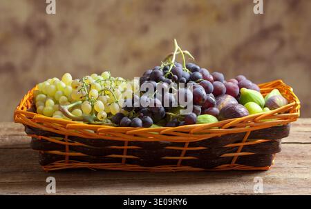 Sweet grapes and figs in basket Stock Photo
