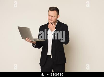 Pensive young caucasian businessman using laptop Stock Photo