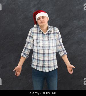 Man in Santa Hat shrugging shoulders in studio Stock Photo