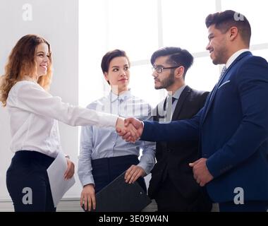 Confident business people shaking hands at workplace Stock Photo