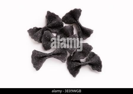 Heap of black farfalle pasta isolated on white Stock Photo