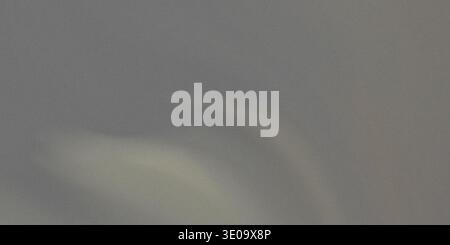 A medium gray textured background showing a fine, slightly visible grain structure. A soft, diffused area of lighter tone appears in the lower central Stock Photo