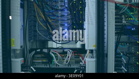 Displaying central rack-mounted servers and switches with glowing LEDs in server room, with cables Stock Photo