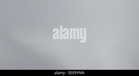 A close-up view of a gray paper texture showing a smooth and slightly shiny surface with subtle variations in tone and a gentle sheen Stock Photo