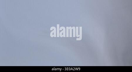 The image shows a light blue fabric texture with gentle folds and creases visible, highlighting its softness and subtlety in a pale and calming color Stock Photo