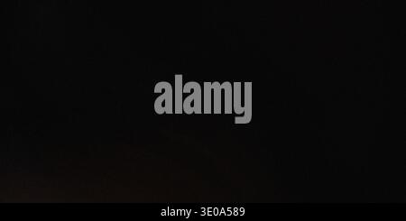 A predominantly deep black background image exhibiting very slight noise or grain. There is a barely perceptible, faint warm glow or light gradient vi Stock Photo