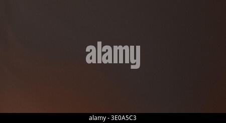 A rich, dark brown textured background exhibiting a fine grain pattern. Subtle warm, almost burnt orange tones appear near the bottom and edges, provi Stock Photo