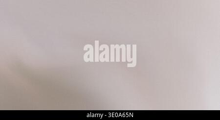 A close-up shot of a very light beige or off-white surface exhibiting a fine, uniform grain texture. The lighting creates subtle tonal variations acro Stock Photo