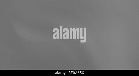 A detailed view of a medium gray textured surface, possibly fabric or brushed metal, showing a consistent fine grain. Slight variations in shading sug Stock Photo