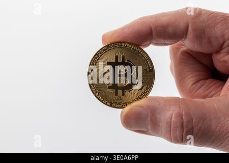 Man's hand holding Bitcoin coin, BTC, obverse, gold-colored, detail, white background, symbol image, virtual currencies, Stock Photo