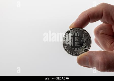 Man's hand holding Bitcoin coin, BTC, front, silver-colored, detail, white background, symbol image, virtual currencies, Stock Photo
