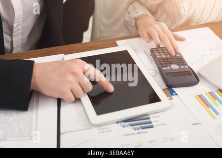 Business colleagues counting on calculator and using tablet Stock Photo