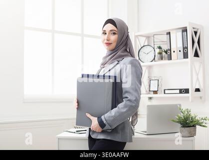 Business Woman Stands With Files in an Office Setting During Daytime Stock Photo
