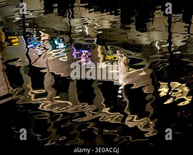 Vibrant night lights create distorted abstract reflections from historic buildings in the dark channel water. Ghent, Belgium. Stock Photo