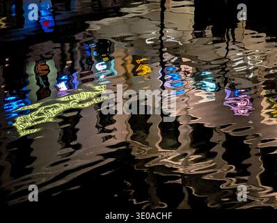 Vibrant night lights create distorted abstract reflections from historic buildings in the dark channel water. Ghent, Belgium. Stock Photo